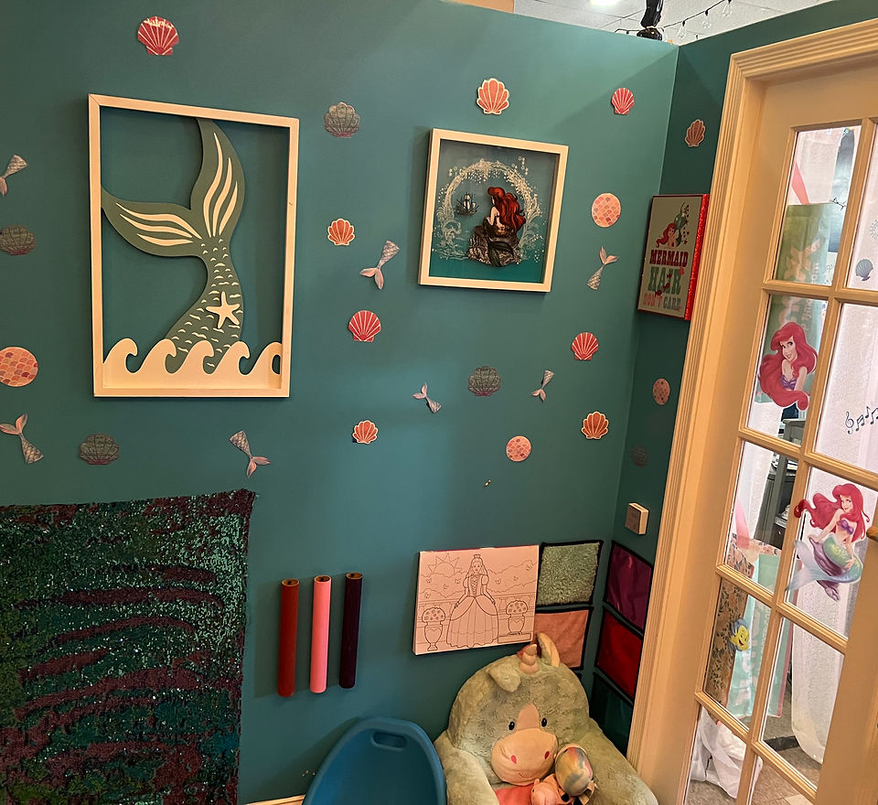 Sensory room wall with mermaid-themed art, seashells and a textured sequin panel