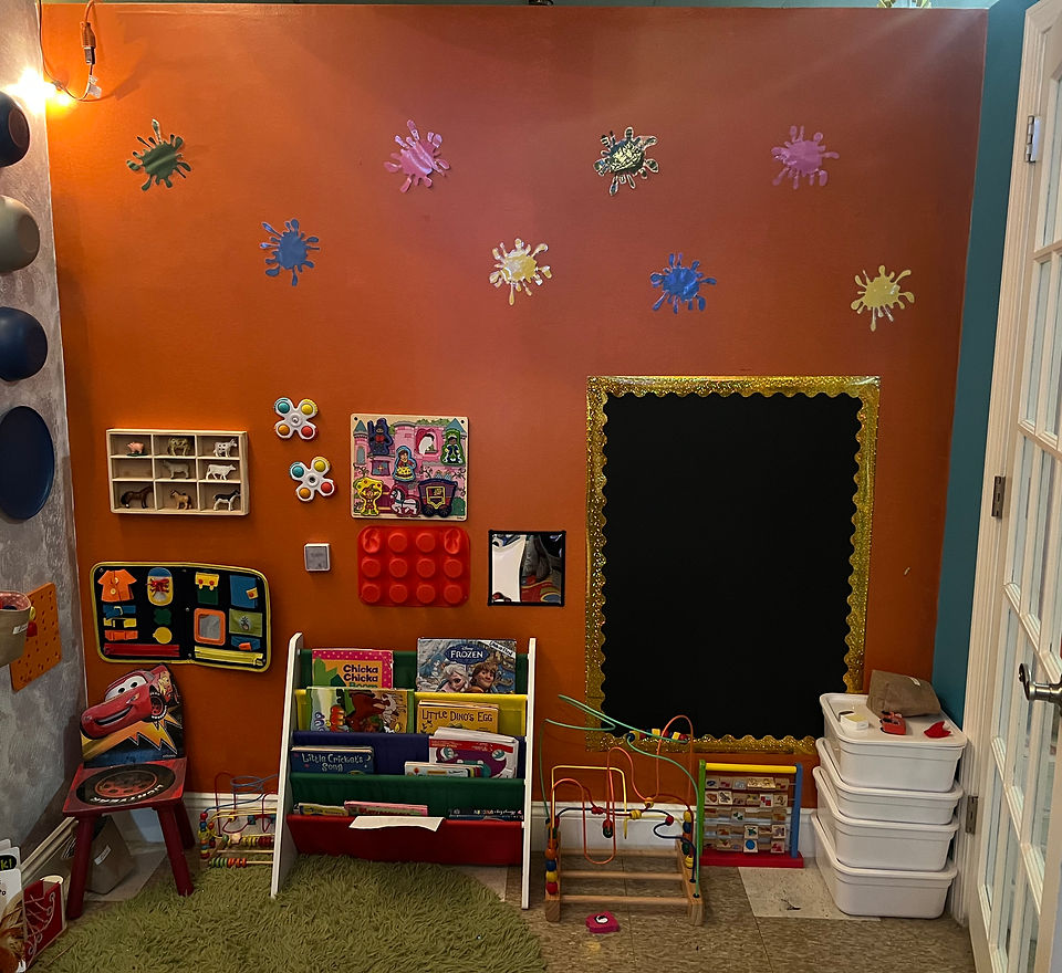 Sensory room corner with busy boards, a book display, a bead maze and a chalkboard