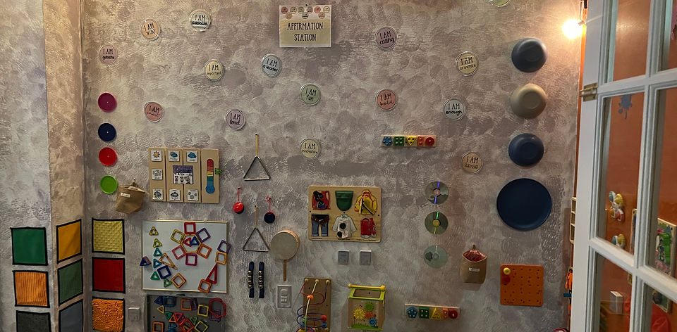 Affirmation station wall with "I am" cards and hands-on latches, switches and musical instruments